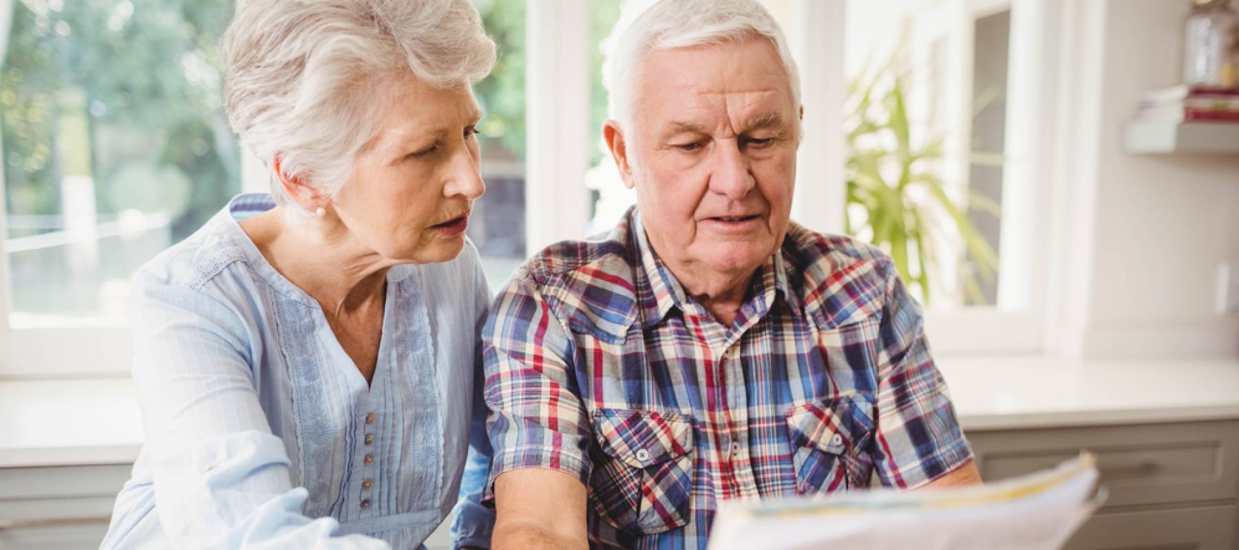 Worried senior couple checking their bills at home.