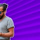 Man with earphones, smartphone and bag on city street and listening to music over ribbed blue wall background