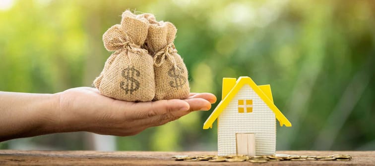 Man holding money bag and home model