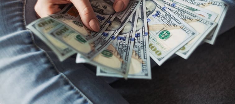 Person holding several 100 dollar notes