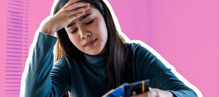 Close up of woman holding her head, looking at multiple credit cards in her hand