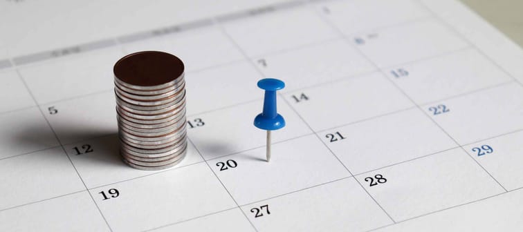 A pile of coins and a blue tack on the calendar.