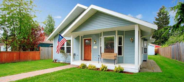 Small clapboard siding house. View of porch with bench and walkway