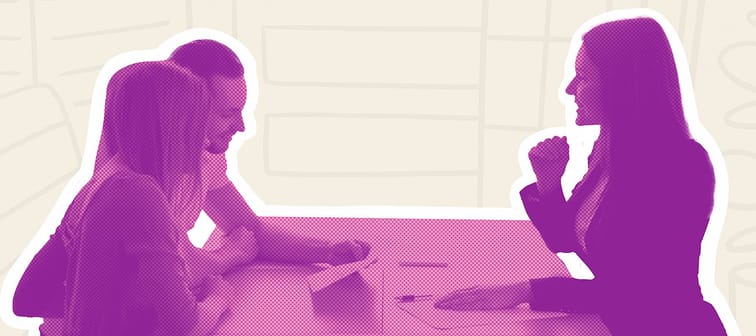 Side view of woman in suit speaking with man and woman across a table in an office