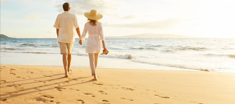 Happy Romantic Middle Aged Couple Enjoying Beautiful Sunset Walk on the Beach. Travel Vacation Retirement Lifestyle Concept