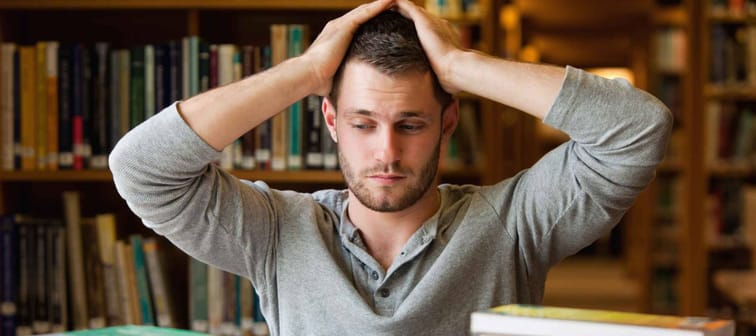 Tired student having too much to do in a library