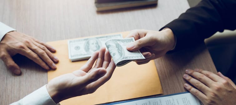 Entrepreneurs are receiving money that is a bribe of their partners with both of whom are corrupt in the company room.